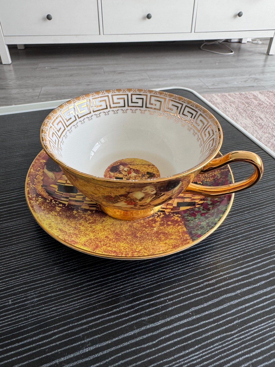 The same teacup from above: a wide hemispherical bowl whose rim flares gently outward, and a long looped gold handle.